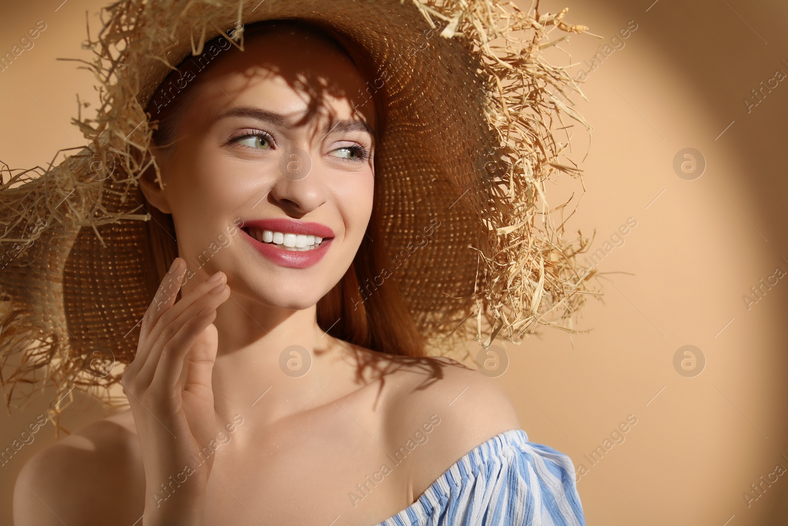 Photo of Beautiful young woman in sunlight on beige background, space for text