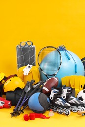 Many different sports equipment on yellow background, space for text