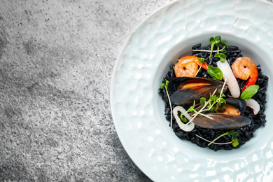 Photo of Delicious black risotto with seafood on grey table, top view