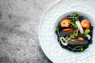 Delicious black risotto with seafood on grey table, top view