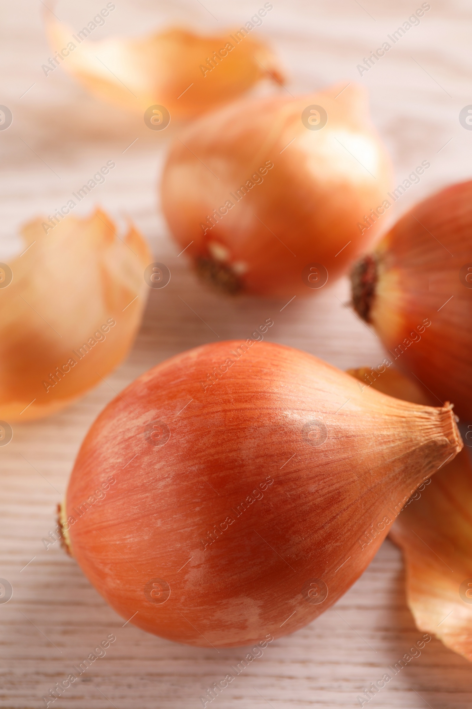 Photo of Raw ripe onions on wooden table, closeup