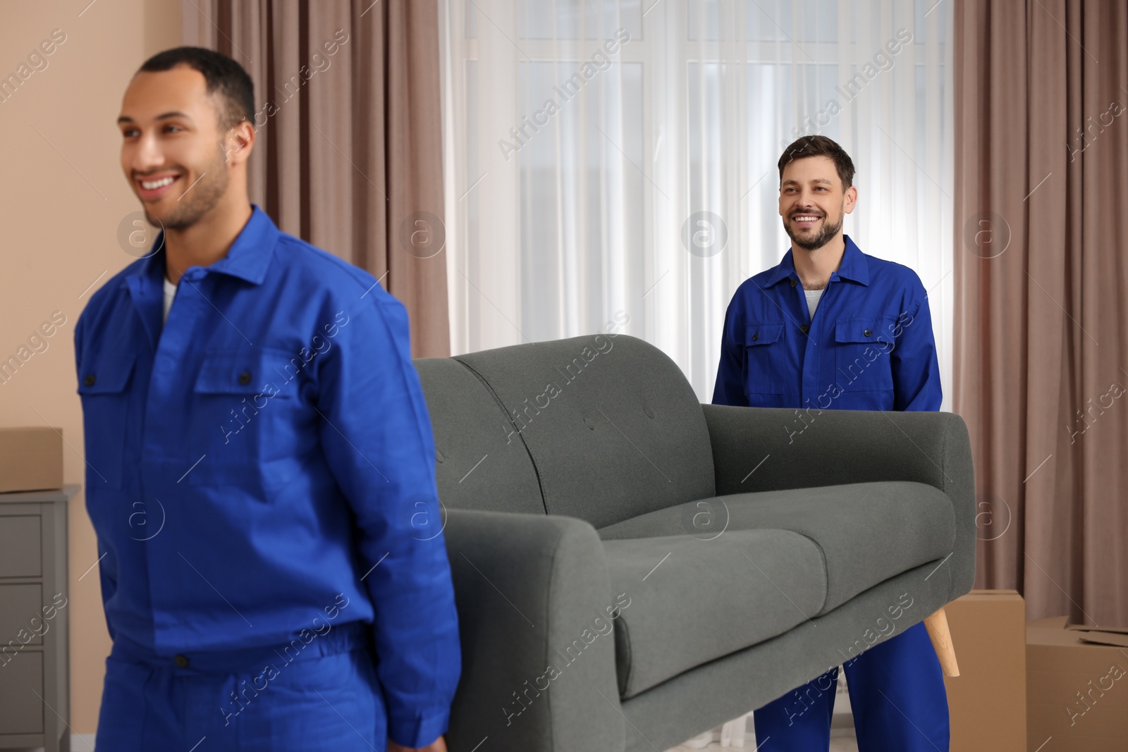 Photo of Male movers carrying sofa in new house