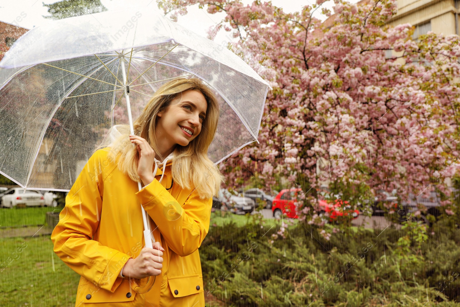 Image of Young woman with umbrella in park on rainy day