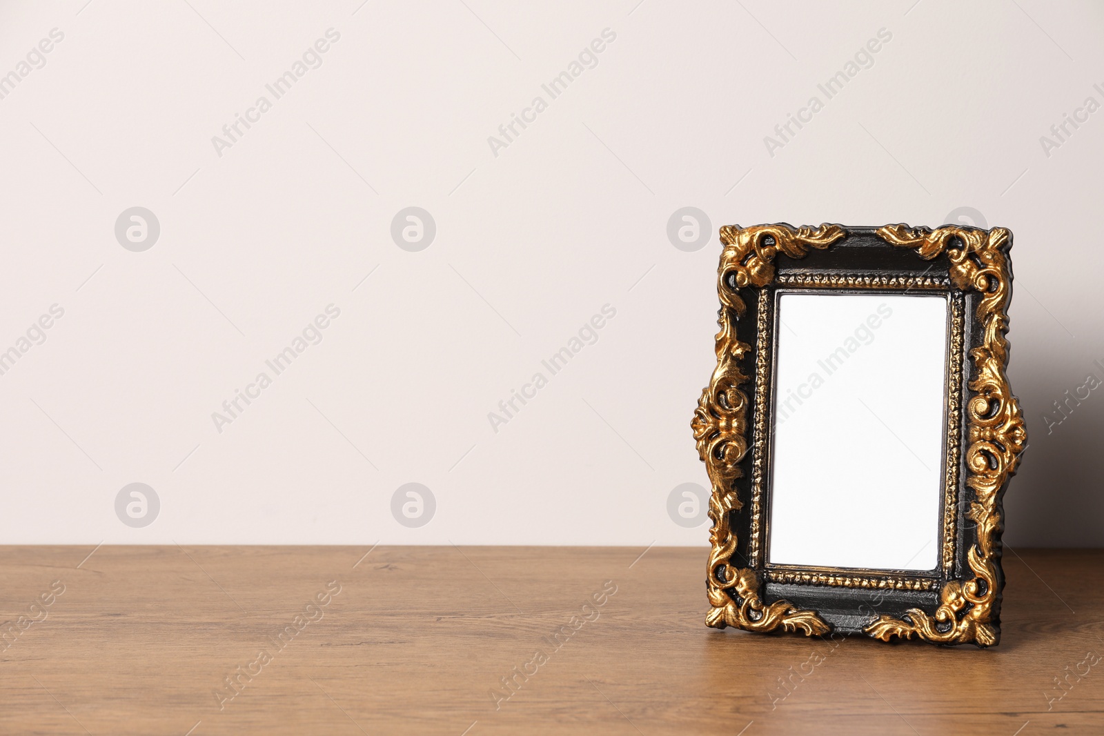 Photo of Beautiful vintage empty frame on wooden table, space for text