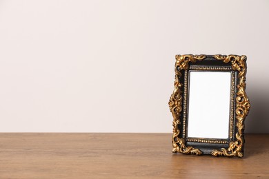 Beautiful vintage empty frame on wooden table, space for text