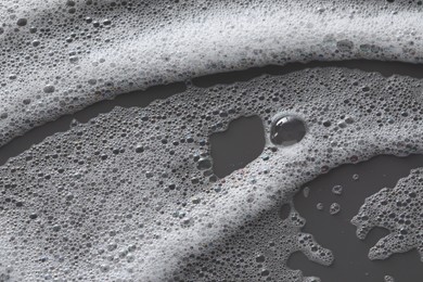 White washing foam on dark gray background, top view