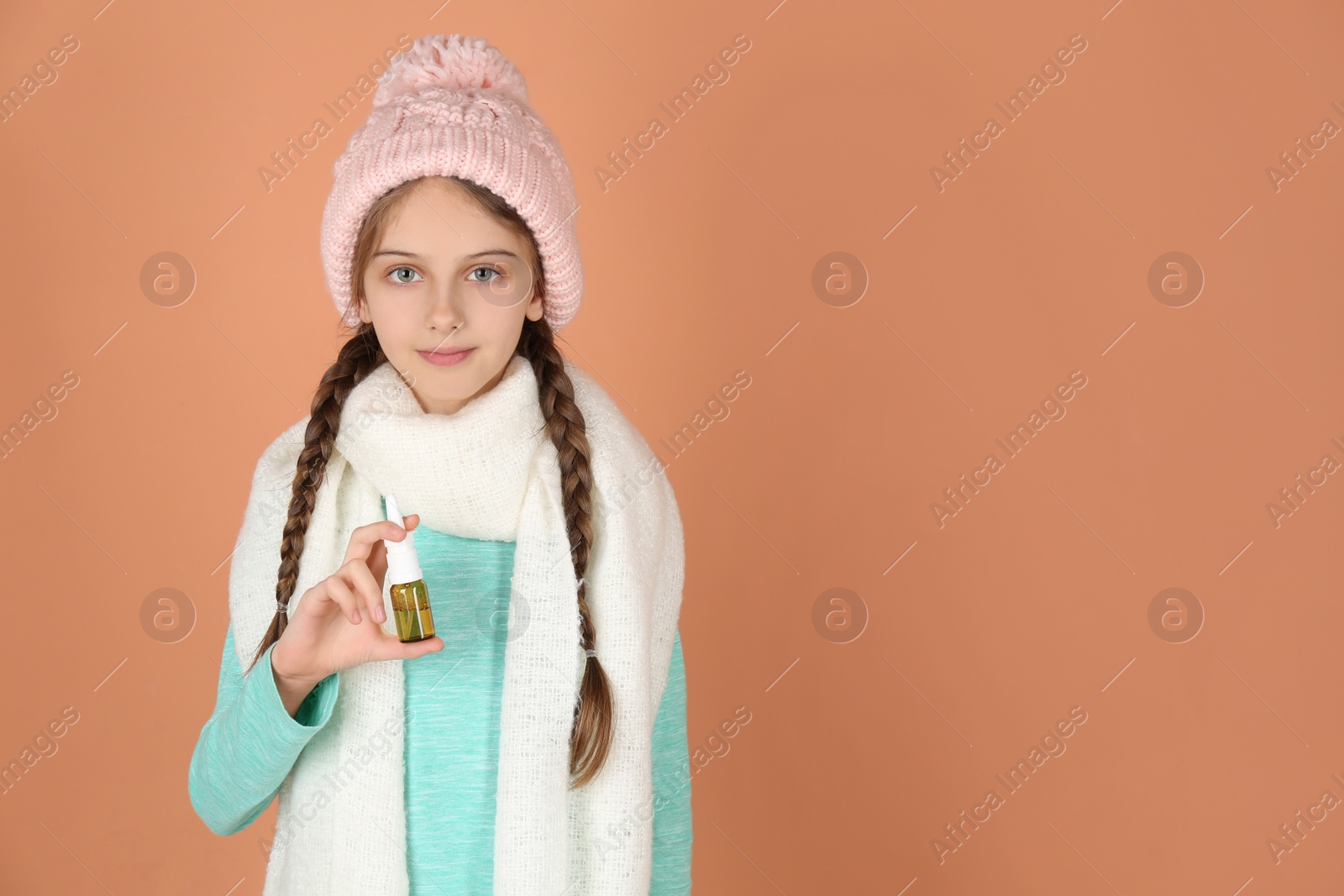 Photo of Sick little girl with nasal spray on coral background. Space for text