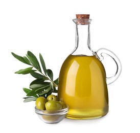 Photo of Glass jug of cooking oil, ripe olives and green leaves isolated on white