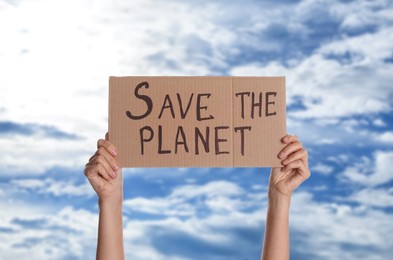 Image of Protestor holding placard with text Save The Planet against blue sky, closeup. Climate strike