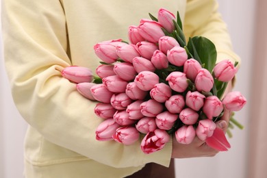 Woman holding bouquet of pink tulips indoors, closeup