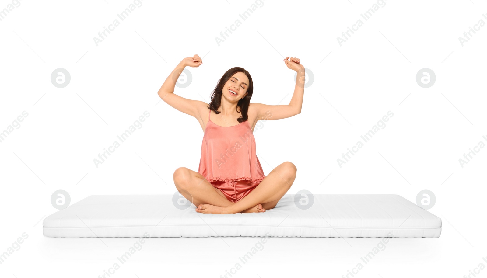 Photo of Young woman stretching on soft mattress against white background