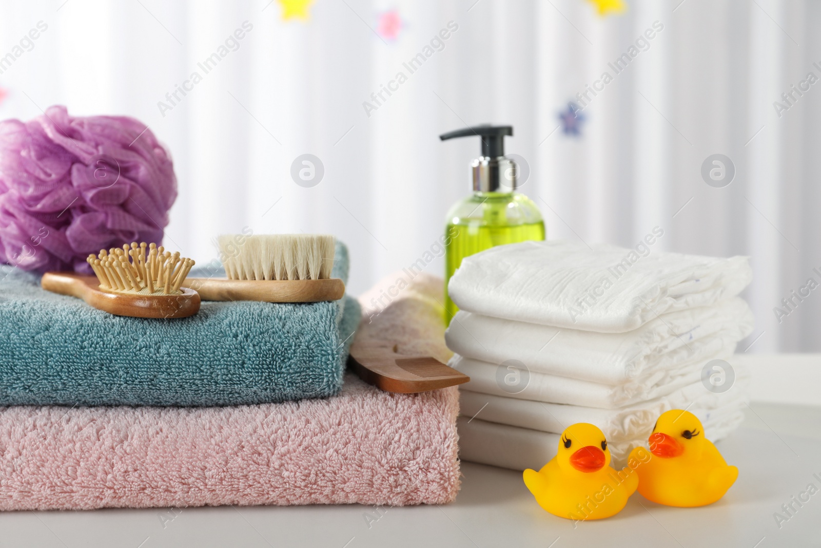 Photo of Towels, rubber ducks and baby care products on white table indoors