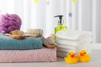 Photo of Towels, rubber ducks and baby care products on white table indoors