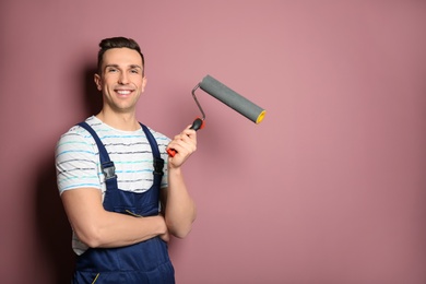 Young male decorator with paint roller near color wall