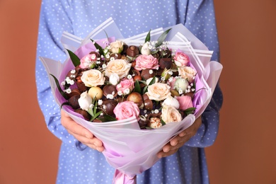 Photo of Woman with beautiful food bouquet on brown background, closeup