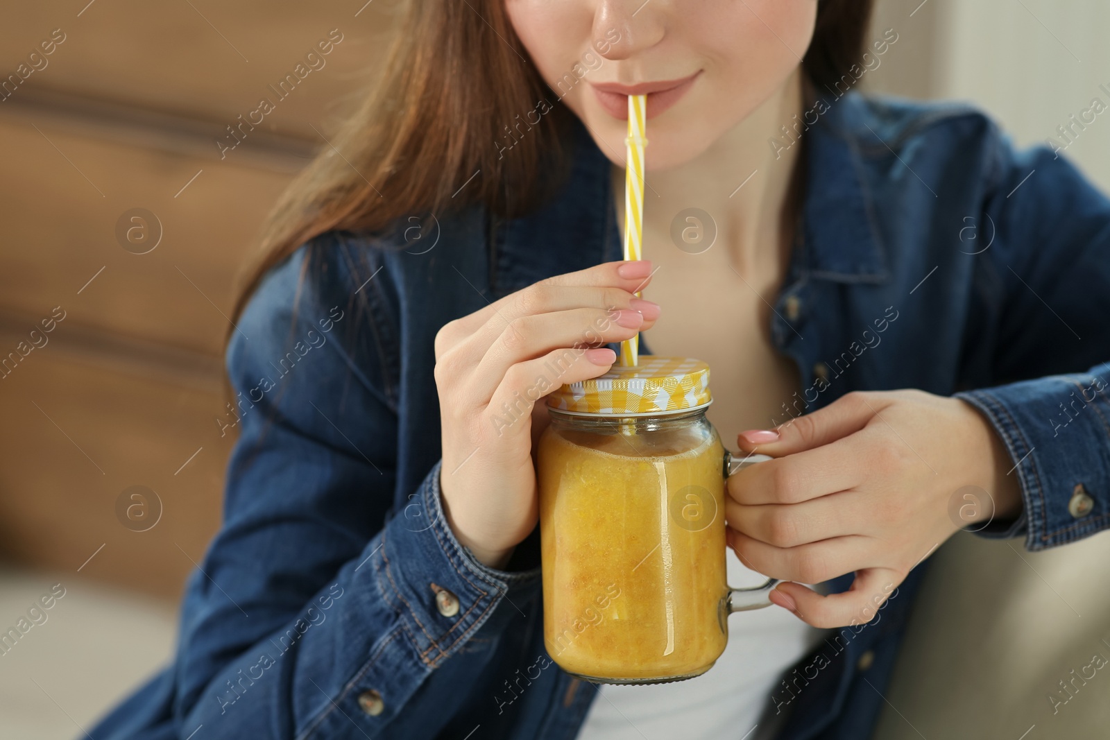 Photo of Woman drinking delicious smoothie indoors, closeup view