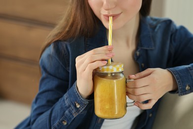 Woman drinking delicious smoothie indoors, closeup view