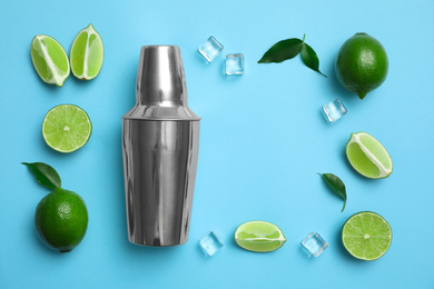 Photo of Flat lay composition with fresh juicy limes, ice cubes and cocktail shaker on light blue background. Space for text