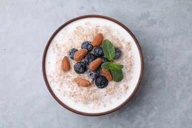 Photo of Tasty wheat porridge with milk, blueberries and almonds in bowl on gray table, top view