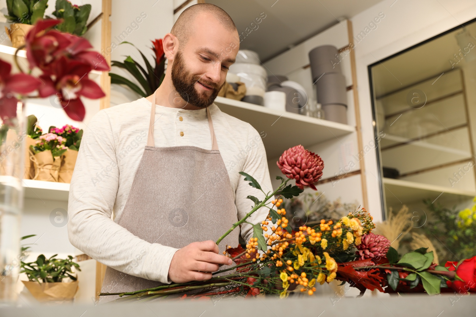 Photo of Florist making bouquet with fresh flowers at table in shop