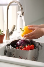 Photo of Woman washing fresh bell pepper in kitchen sink, closeup