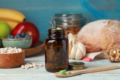 Photo of Bottle of pills and foodstuff on white wooden table. Prebiotic supplements