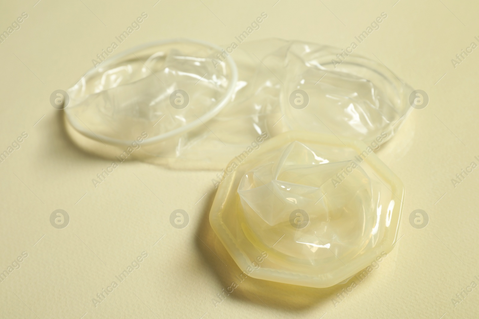 Photo of Female condoms on beige background, closeup. Safe sex