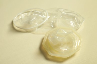 Female condoms on beige background, closeup. Safe sex