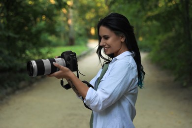 Beautiful woman with camera spending time in nature reserve