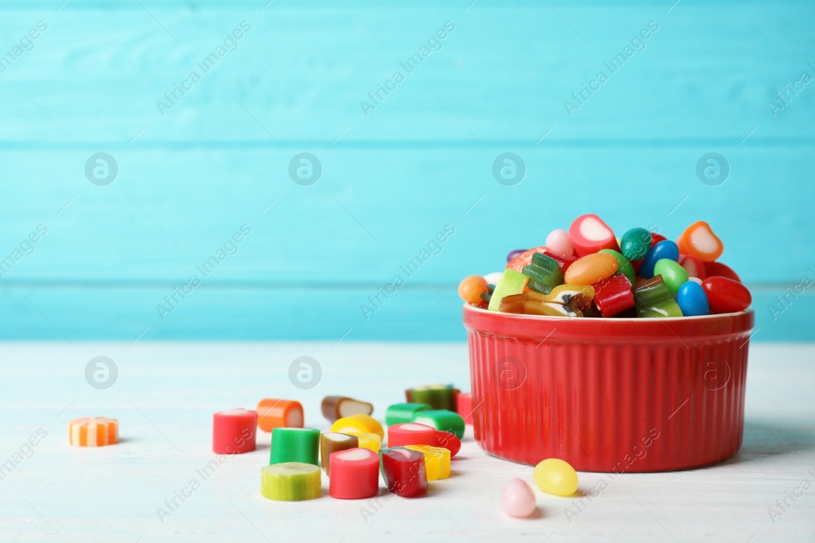 Photo of Bowl with delicious colorful candies on table against wooden background. Space for text