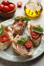 Photo of Tasty sandwiches with cured ham, basil and tomatoes on table, closeup