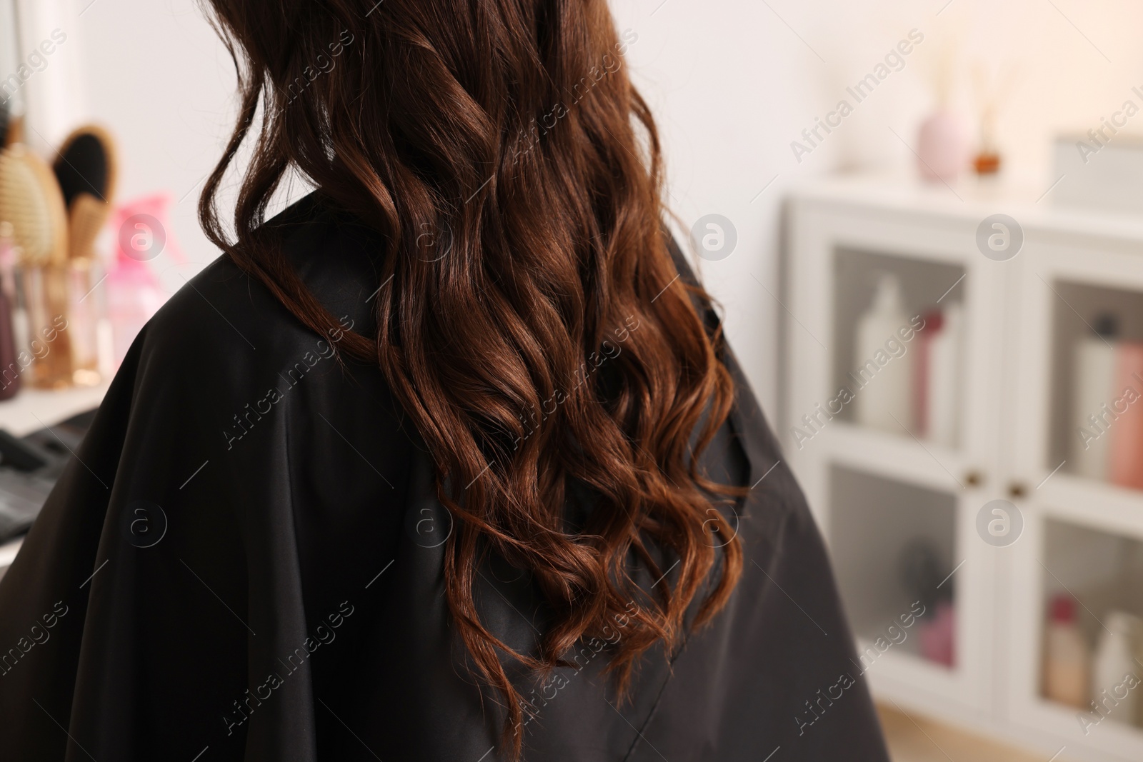 Photo of Woman with curly hair sitting in salon, closeup