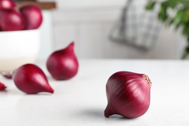 Photo of Fresh whole red onion bulb on white wooden table. Space for text