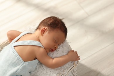 Photo of Cute newborn baby sleeping in white wicker basket indoors, above view. Space for text