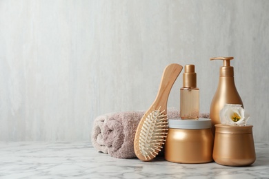 Different hair products, towel and brush on white marble table. Space for text