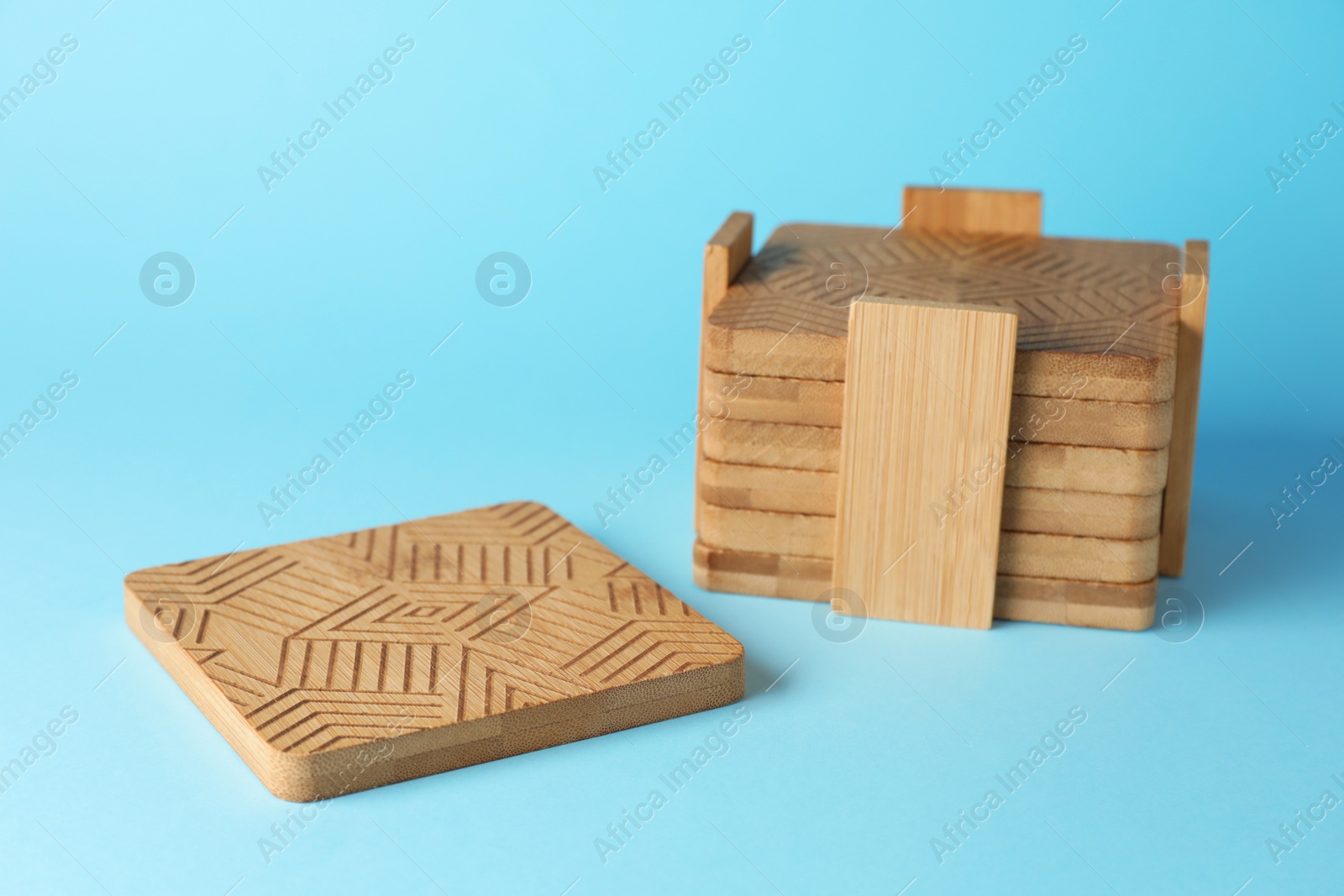 Photo of Stylish wooden cup coasters on light blue background