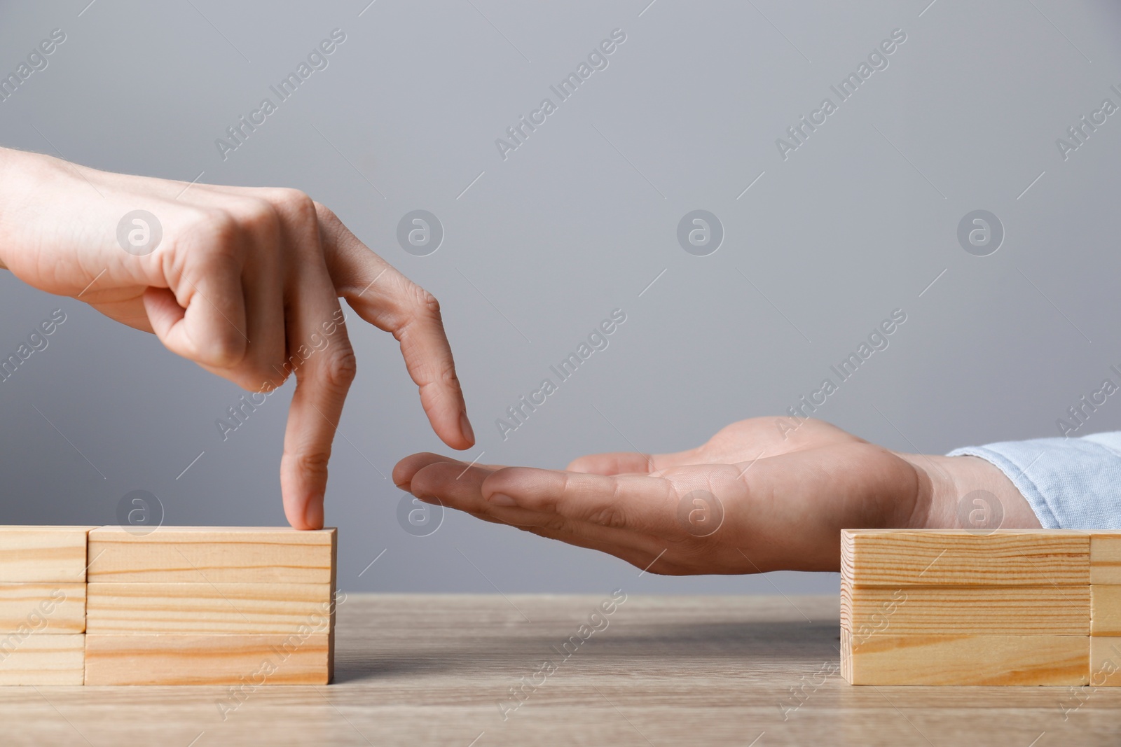 Photo of Woman helping her partner to cross unfinished bridge at wooden table, closeup. Connection, relationships and deal concept