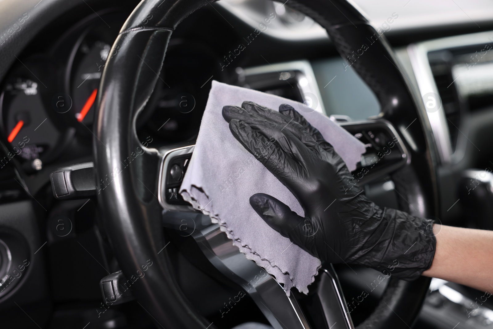 Photo of Woman wiping her modern car with rag, closeup