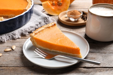 Plate with piece of fresh delicious homemade pumpkin pie on wooden table