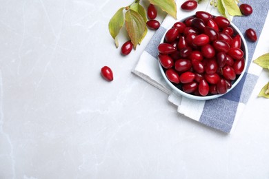 Fresh ripe dogwood berries, leaves and napkin on light grey table, flat lay. Space for text