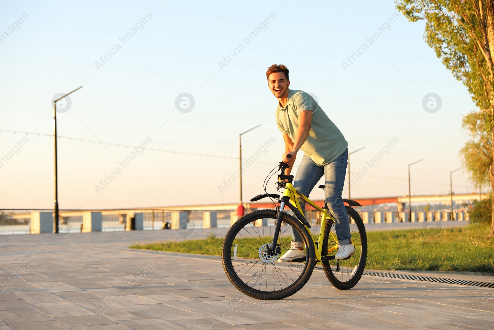 Photo of Handsome young man riding bicycle on city waterfront