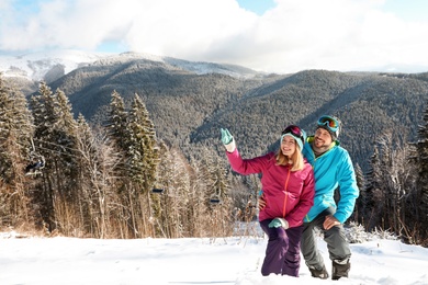 Photo of Happy couple spending winter vacation in mountains. Space for text