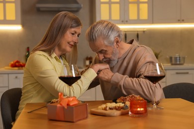 Affectionate senior couple having romantic dinner at home