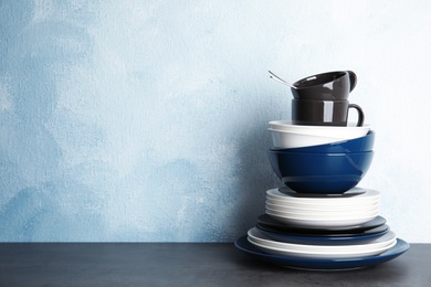 Photo of Set of dinnerware on table against color background with space for text. Interior element