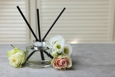 Photo of Reed air freshener and flowers on grey table indoors
