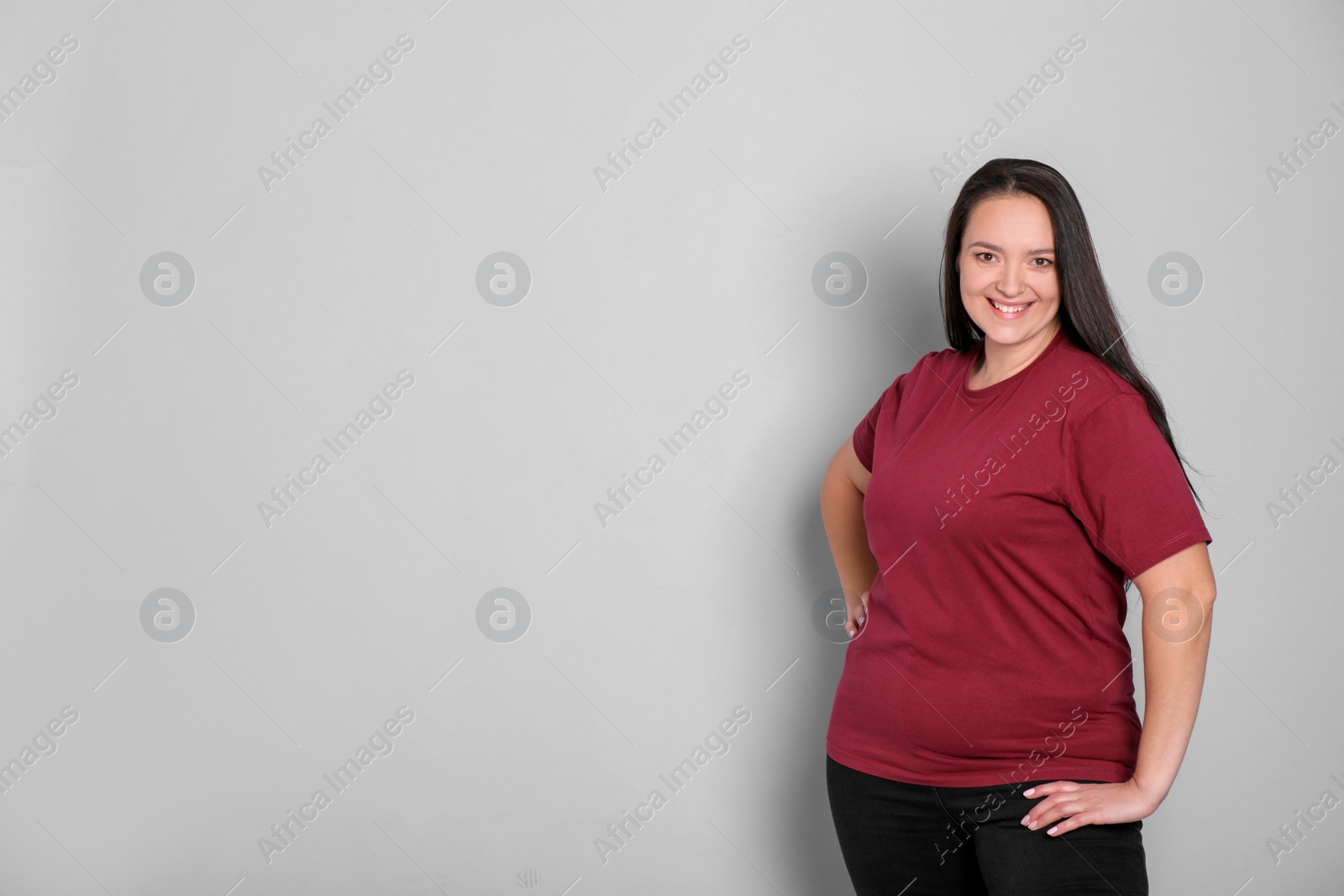 Photo of Beautiful overweight woman with charming smile on light grey background. Space for text