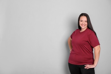 Photo of Beautiful overweight woman with charming smile on light grey background. Space for text