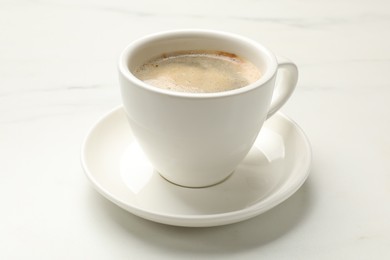 Cup of aromatic coffee on white table, closeup