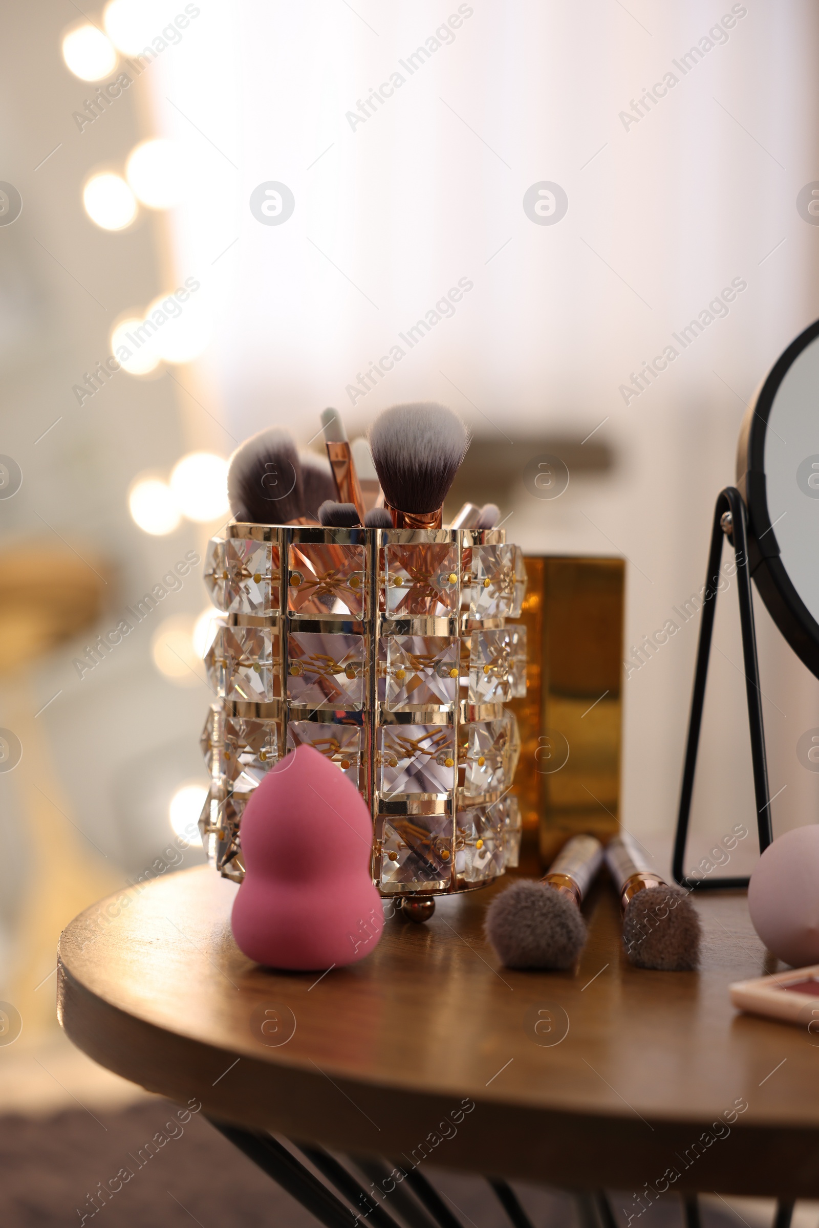 Photo of Makeup brushes and sponge on wooden table in room