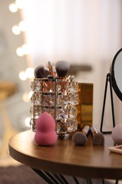 Photo of Makeup brushes and sponge on wooden table in room